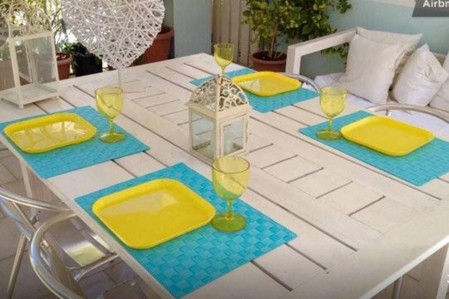 Ein Esstisch mit gelben Platzsets, grünem Glas und einem weißen Laternen-Zentrum.