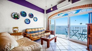 Enjoy the ocean view from the large window in this living area, featuring a sofa, coffee table, and side table.