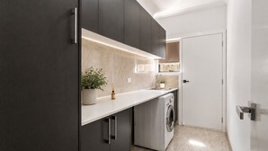 Una cocina moderna con armarios oscuros, una encimera, una lavadora y una puerta.