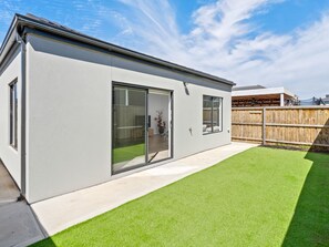 A modern house with a large sliding glass door, a fenced backyard, and a well-maintained lawn. - SARA by Ready Set Stay - 3 Bedrooms, Family Friendly Holiday House (Fraser Rise)