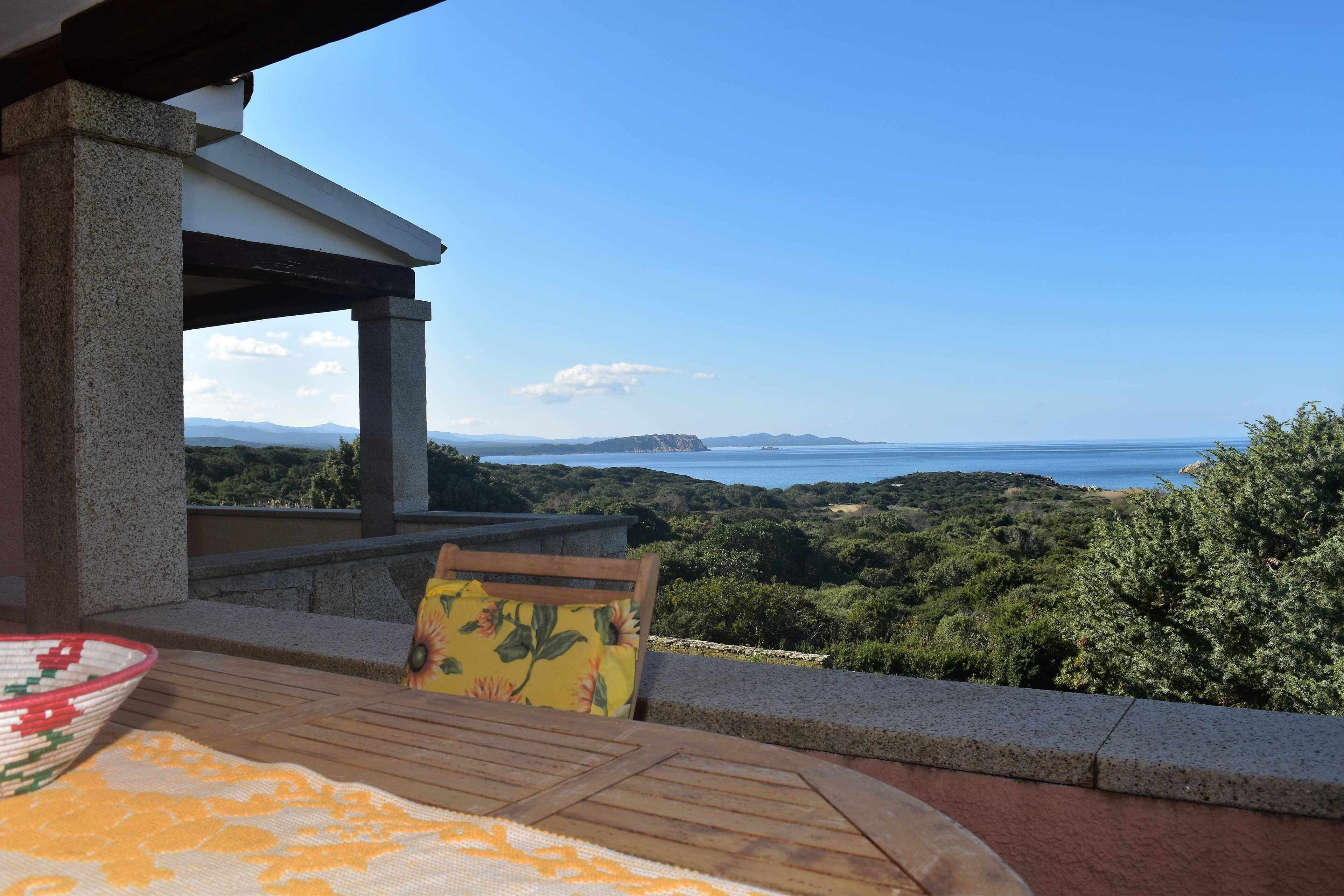 Un balcon avec vue sur la mer et les collines.