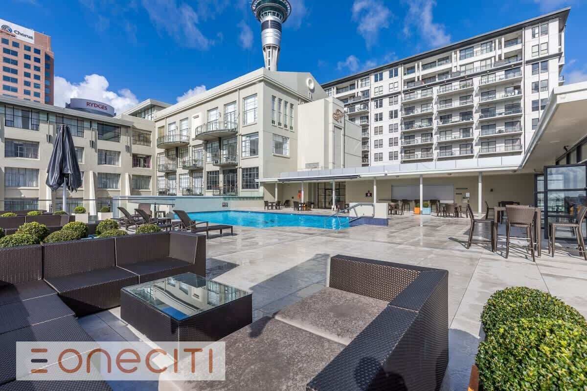 Ein Poolbereich auf dem Dach mit Liegemöglichkeiten und Blick auf ein Hochhaus.