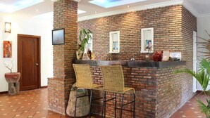 A reception area with a brick wall, two wicker chairs, a counter, and a door.