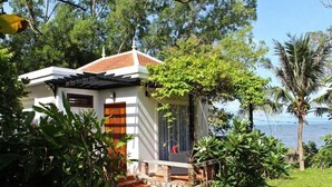 A small white building with a tiled roof, surrounded by lush greenery and a palm tree. - Sabbay Kep (Kep)