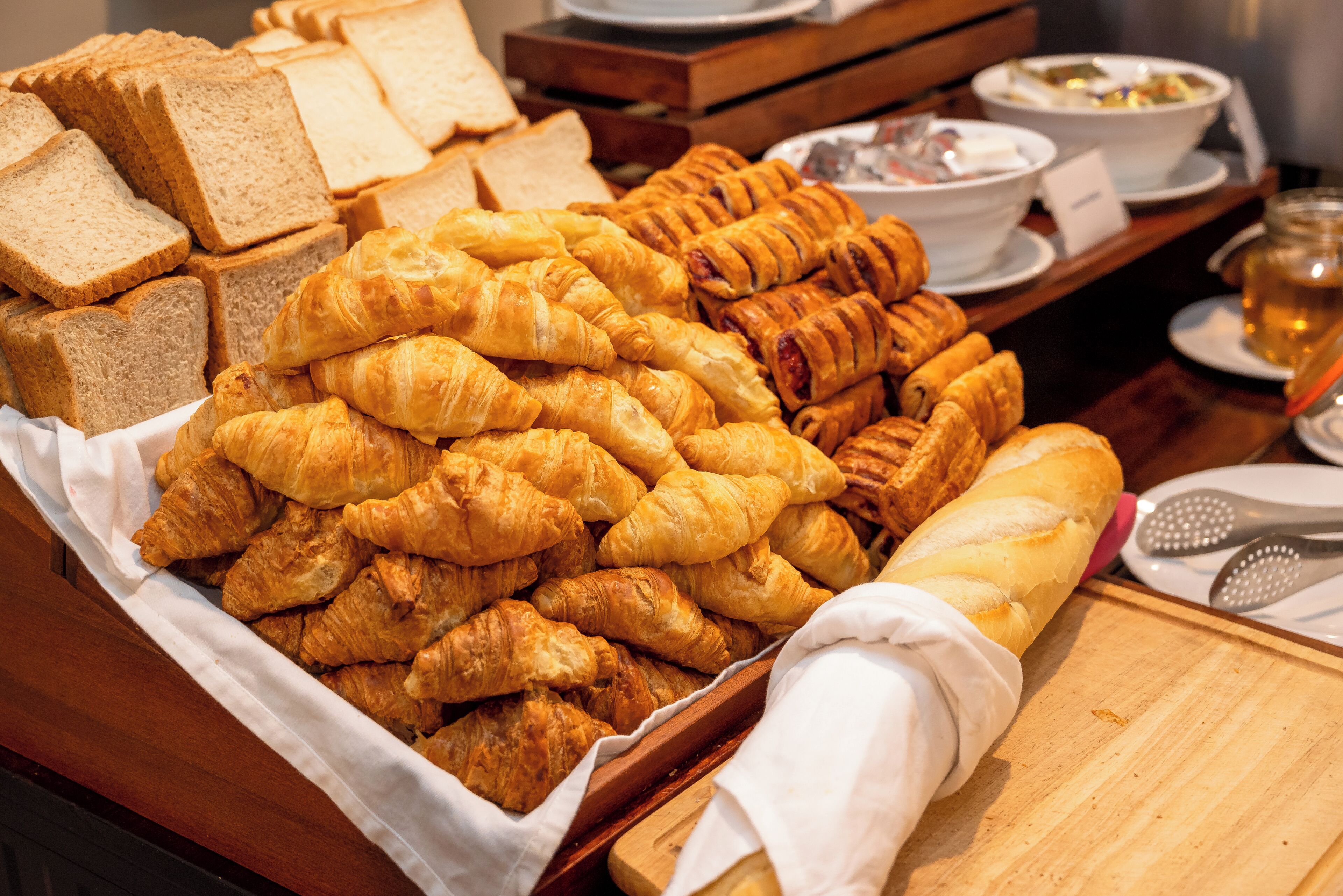 A variety of pastries and bread on a buffet table.