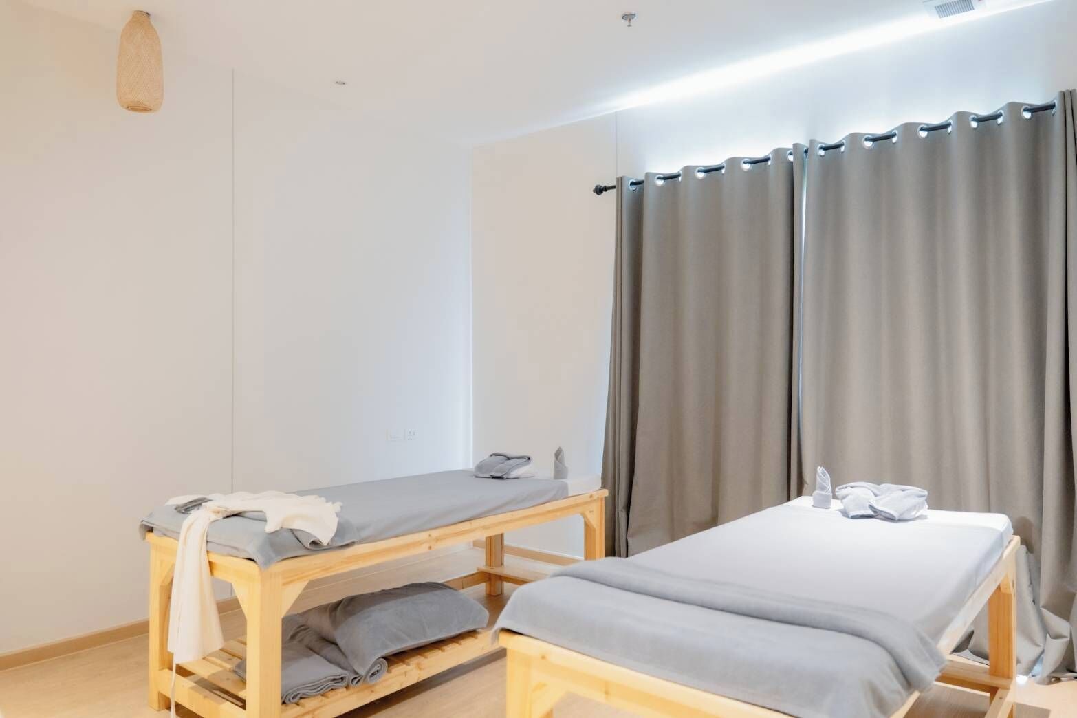 A room with two wooden beds, a small table, and a curtain.