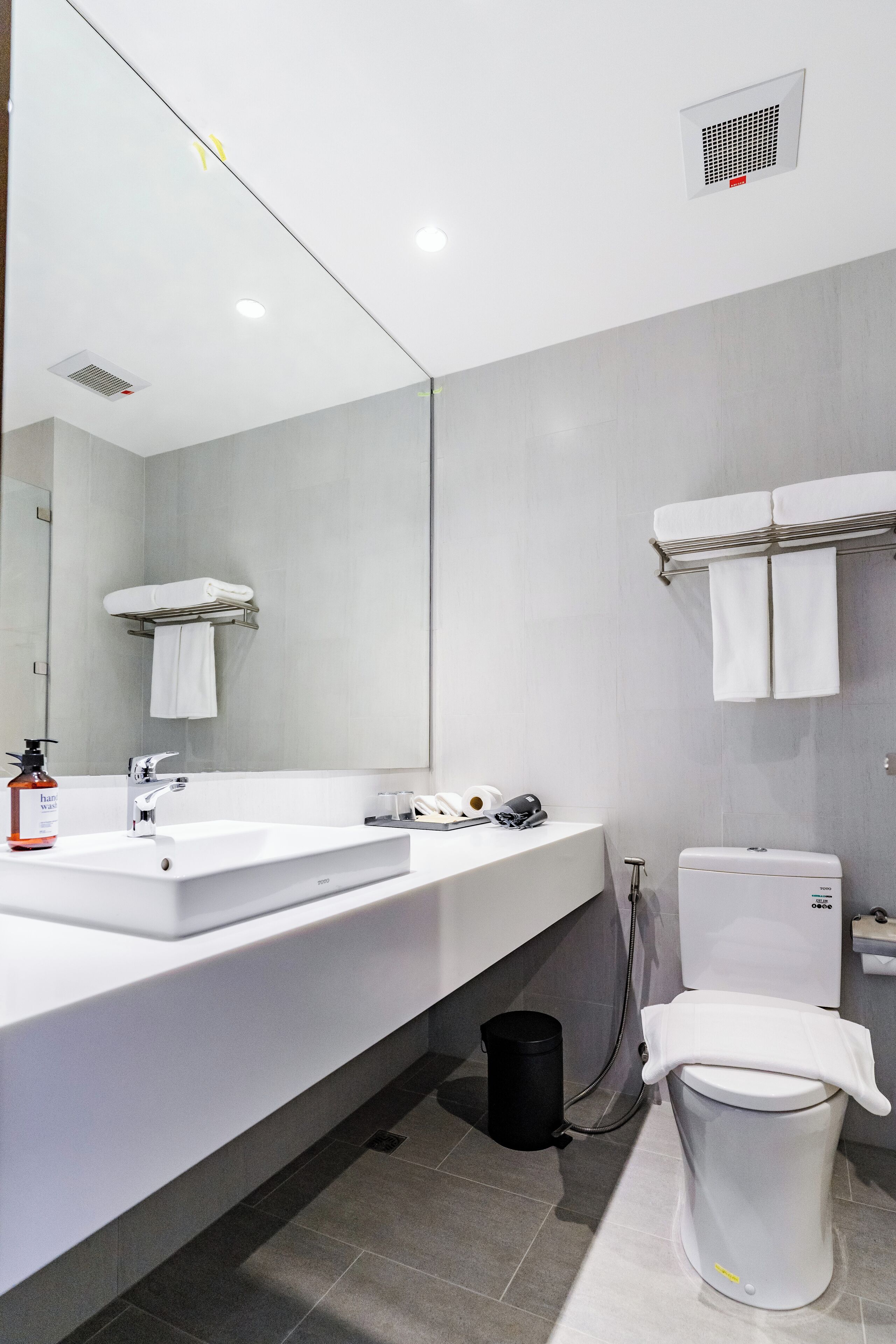Een moderne badkamer met een witte wastafel, spiegel en toilet.