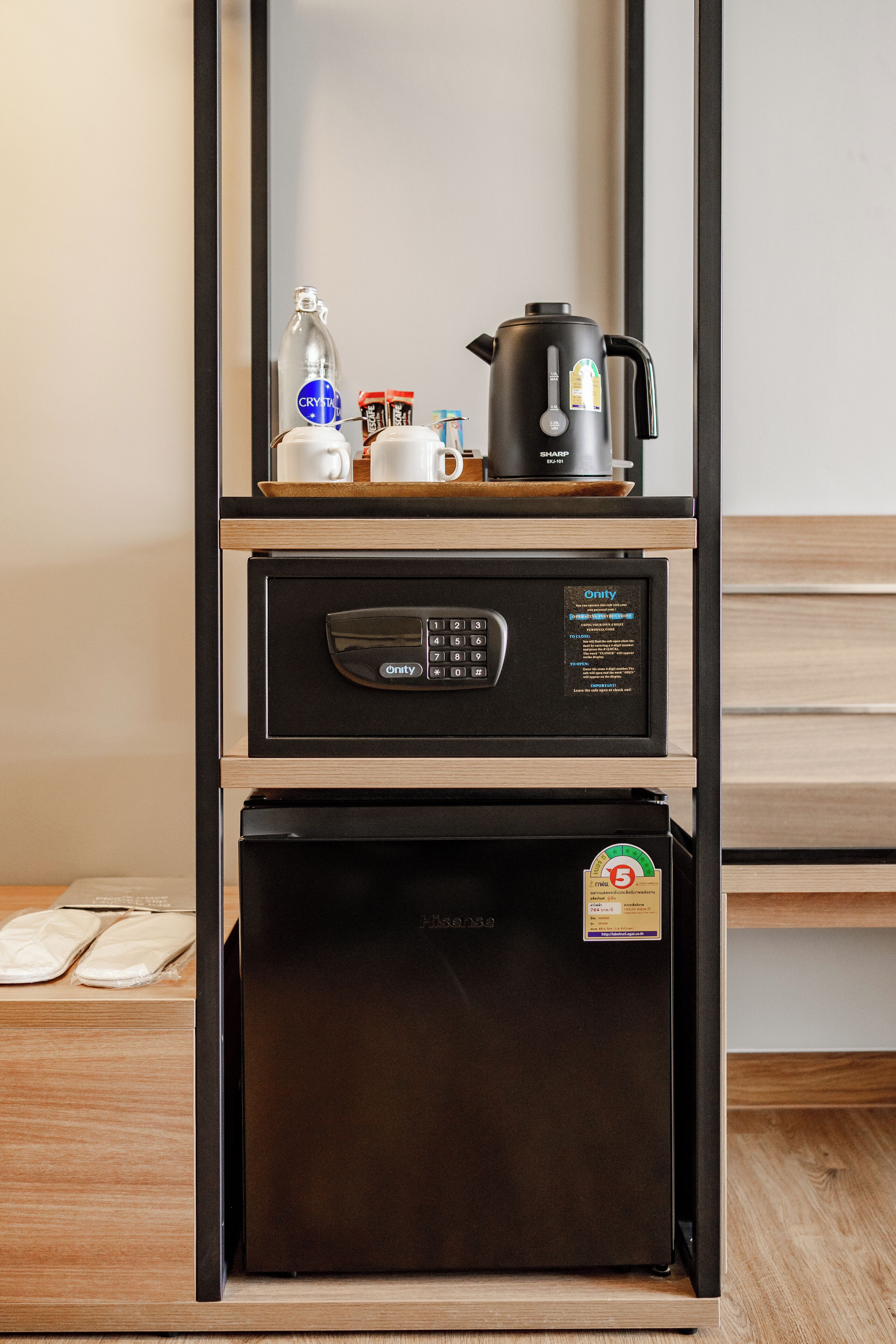 A compact kitchen area with a coffee maker, a kettle, and a small refrigerator.