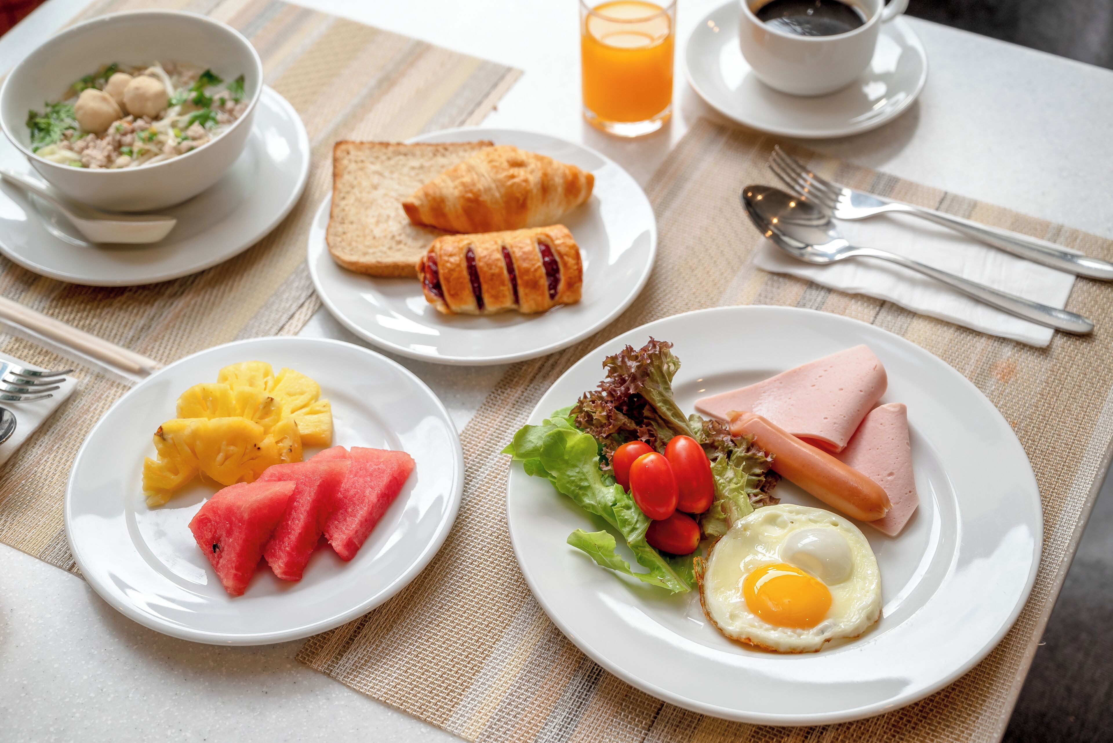 Una escena de desayuno con platos de comida, un tazón y una taza de café.