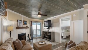 A living room with a fireplace, a television, and a balcony with a bed.