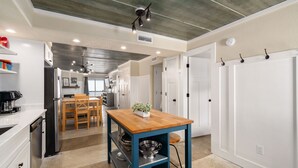 A modern kitchen with white cabinetry, a wooden table, and a blue accent wall.