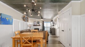 A modern kitchen with a wooden dining table and chairs, a ceiling fan, and white cabinetry.