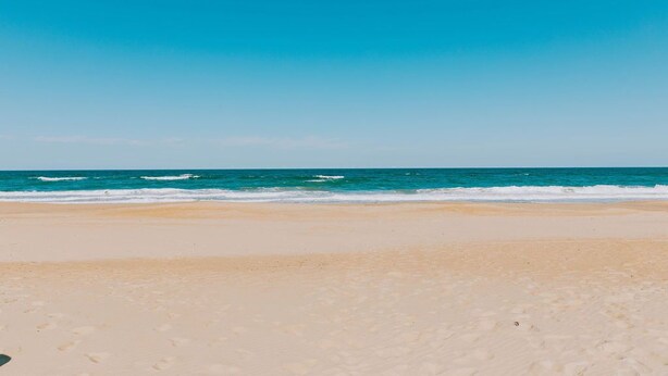 A beach with a clear sky and calm sea.