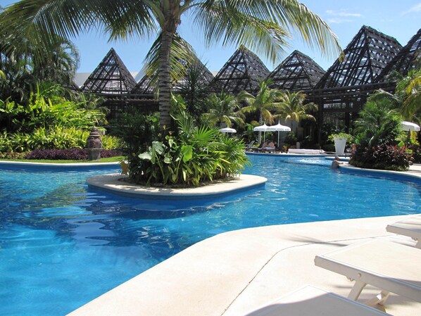 A swimming pool with lounge chairs and palm trees.