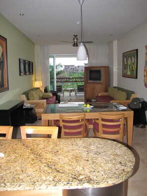A modern living room with a dining area, a ceiling fan, and a view of the outdoors.