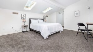 A bedroom with a bed, a desk, and a chair. There are skylights on the ceiling. - Exquisite Downtown Loft Apartment (Hartford)