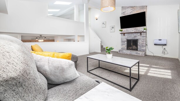 A modern living room with a grey sofa, a coffee table, and a fireplace. - Exquisite Downtown Loft Apartment (Hartford)