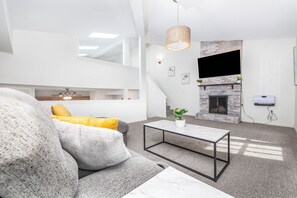 A modern living room with a grey sofa, a coffee table, and a fireplace. - Exquisite Downtown Loft Apartment (Hartford)