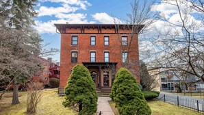 A brick building with a central entrance, flanked by two symmetrical trees, and a clear sky. - Exquisite Downtown Loft Apartment (Hartford)