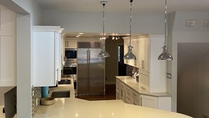 A modern kitchen with a central island, stainless steel appliances, pendant lighting, and bar stools. - Luxury Home For Rent NBA All Star Weekend (Salt Lake City)