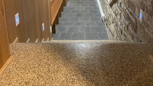 A narrow hallway with wooden walls and a stone wall at the end. There are benches along the left wall and a door at the end of the hallway. - Luxury Home For Rent NBA All Star Weekend (Salt Lake City)