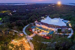 An aerial view of a large, uniquely shaped building surrounded by dense forest, with a curved pathway leading to it. - 617 Sands Dr · 3 Bedroom Brand New House Near Beach | King Bed (St. Augustine)