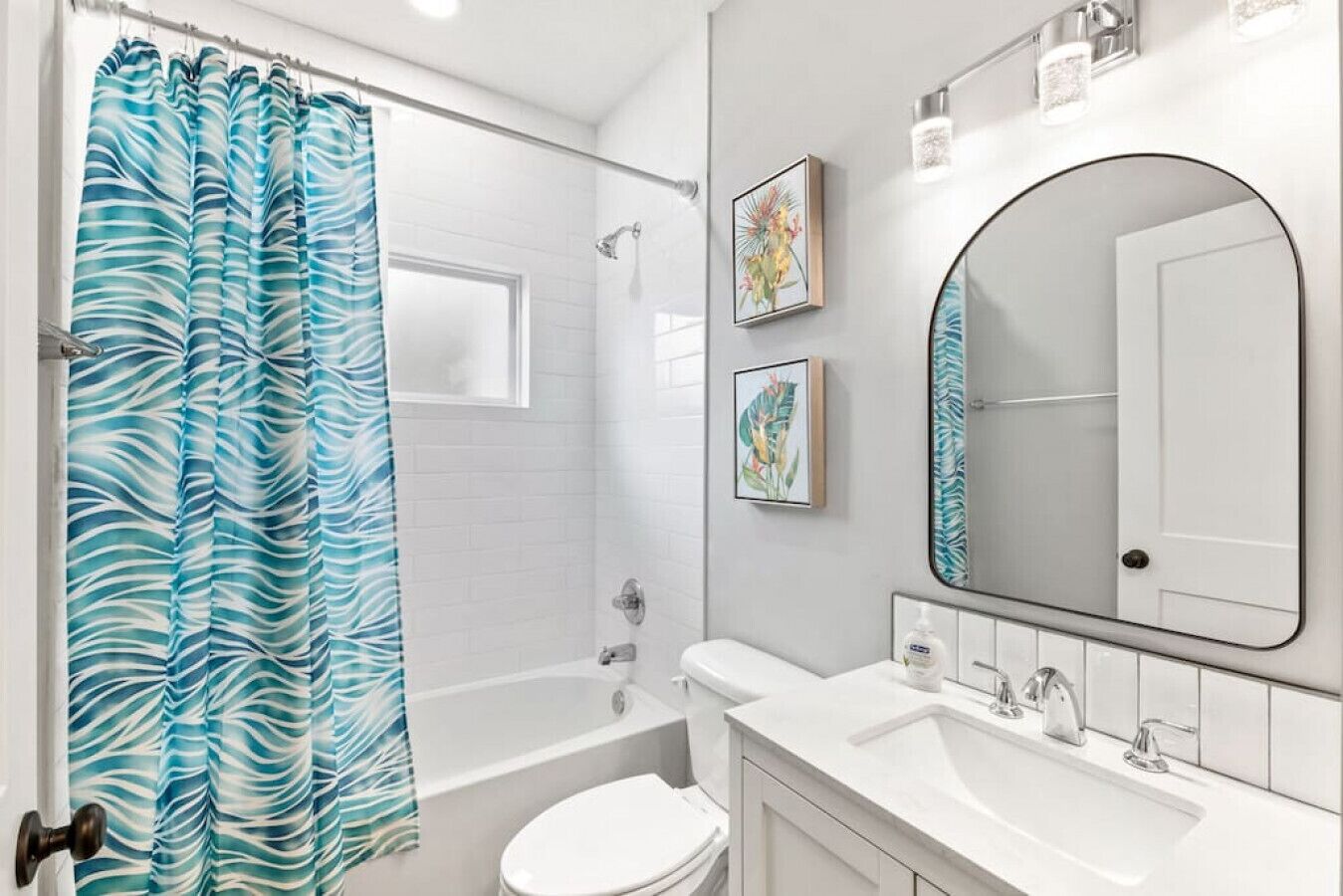 A bathroom with a shower, toilet, sink, and a large mirror.