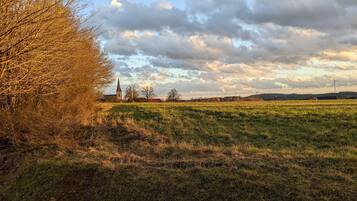A rural landscape with a church, wind turbines, and open fields.