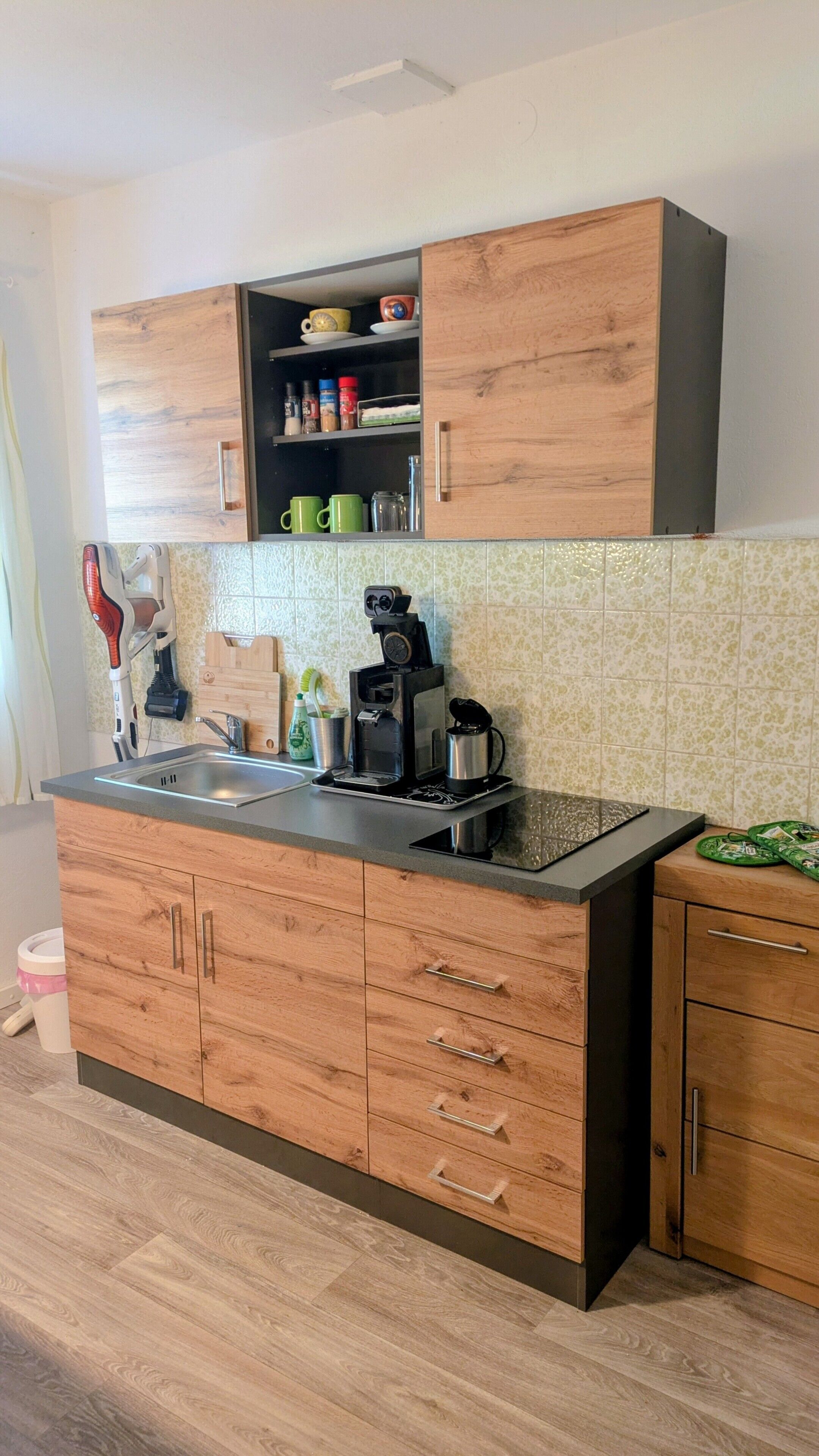 Een keuken met houten kastjes, een koffiezetapparaat en een spoelbak.
