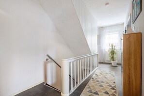 A staircase with a white railing, a potted plant, and a patterned rug.