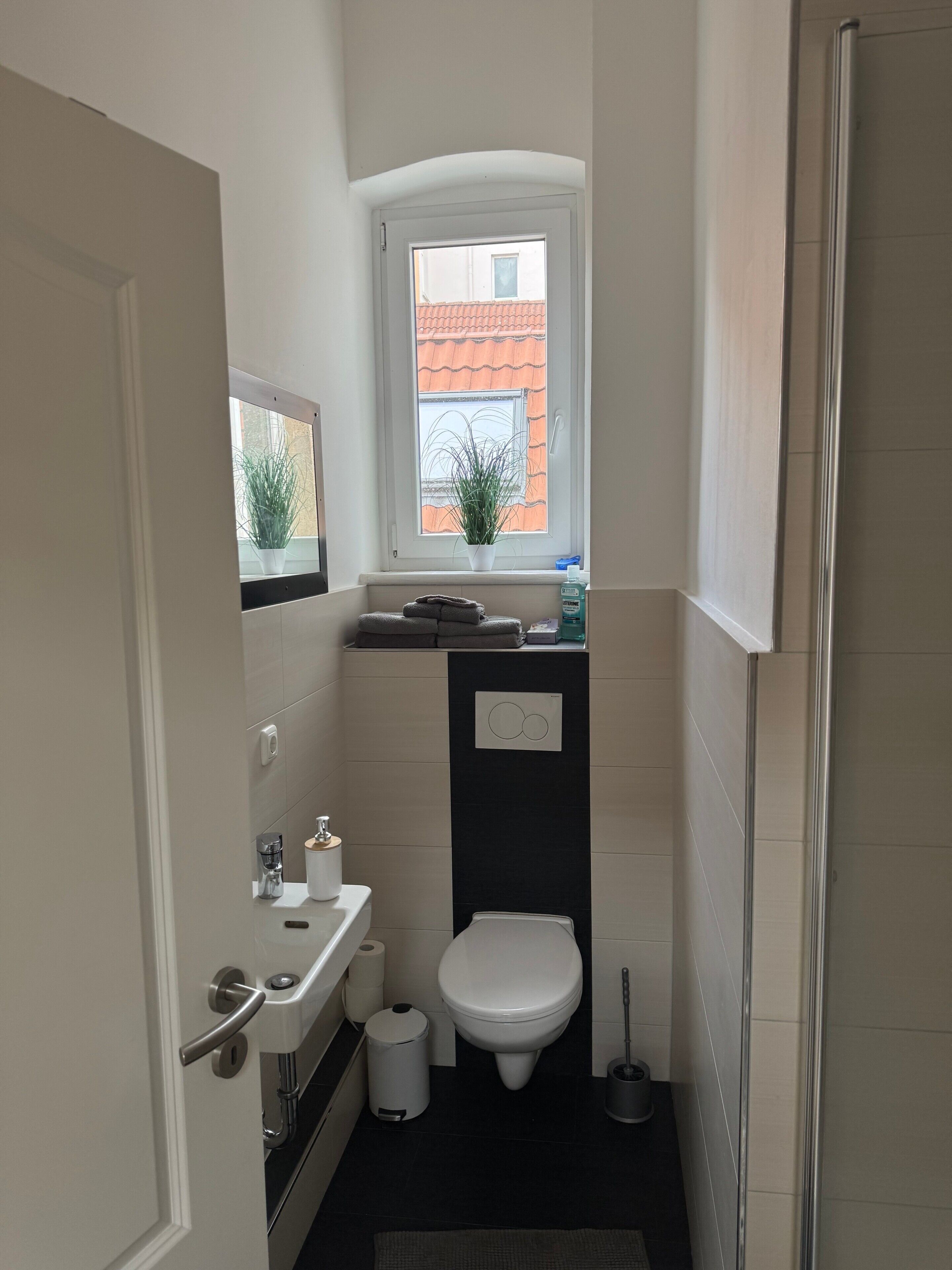 Une petite salle de bain comprenant des toilettes, un lavabo et une fenêtre.