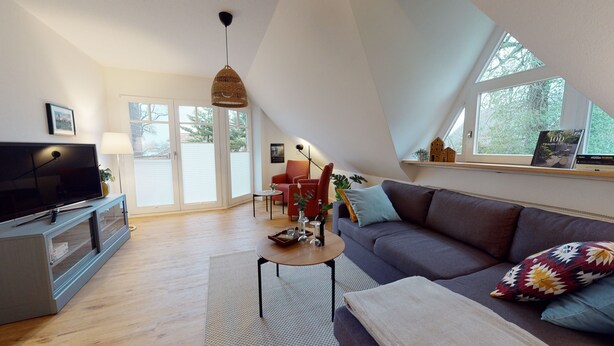 Un loft moderno con un televisor grande, un sofá, una mesa de comedor y una estantería.