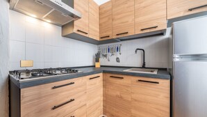 A modern kitchen with wooden cabinets, a stainless steel refrigerator, and a gas stove. - Palm Villa - Seaside Vacation (Muravera)