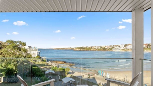 Een balkon met helder uitzicht op zee en een strand.