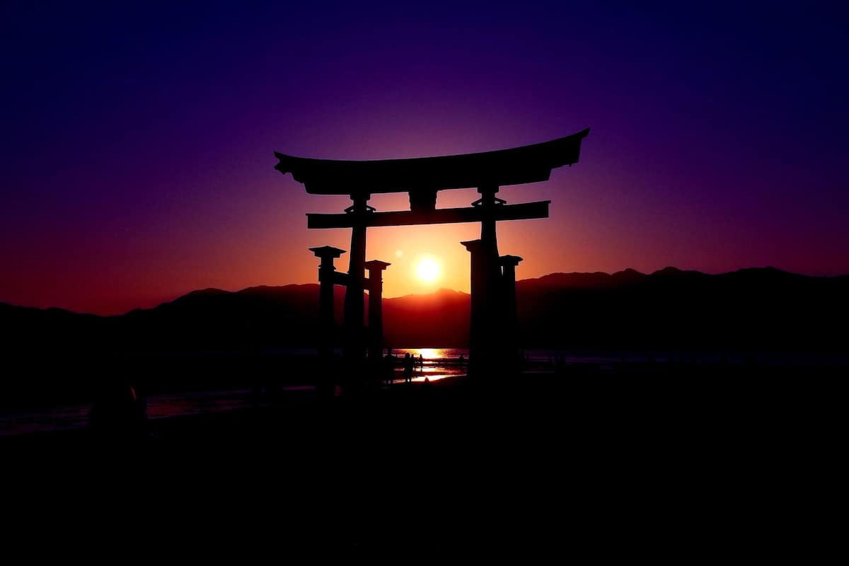 A traditional Japanese torii gate silhouetted against a sunset.