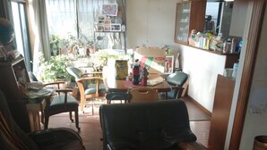 A living room with a sofa, a coffee table, and a dining area with a table and chairs. - Full House Miyajima (Hatsukaichi)