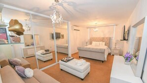 A modern bedroom with a large bed, a sitting area with a sofa, and a glass partition. - Tropical Haven with private pool (Carolina)