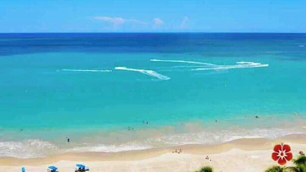 A beach with clear turquoise water, a sandy shore, and a few umbrellas. - Tropical Haven with private pool (Carolina)