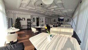 A dining area with white tables and chairs, a chandelier, and a Christmas tree. - HL 309 Hotel (Tashkent)