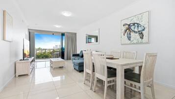 Un salon moderne avec un coin repas, une grande fenêtre et une vue sur la ville.