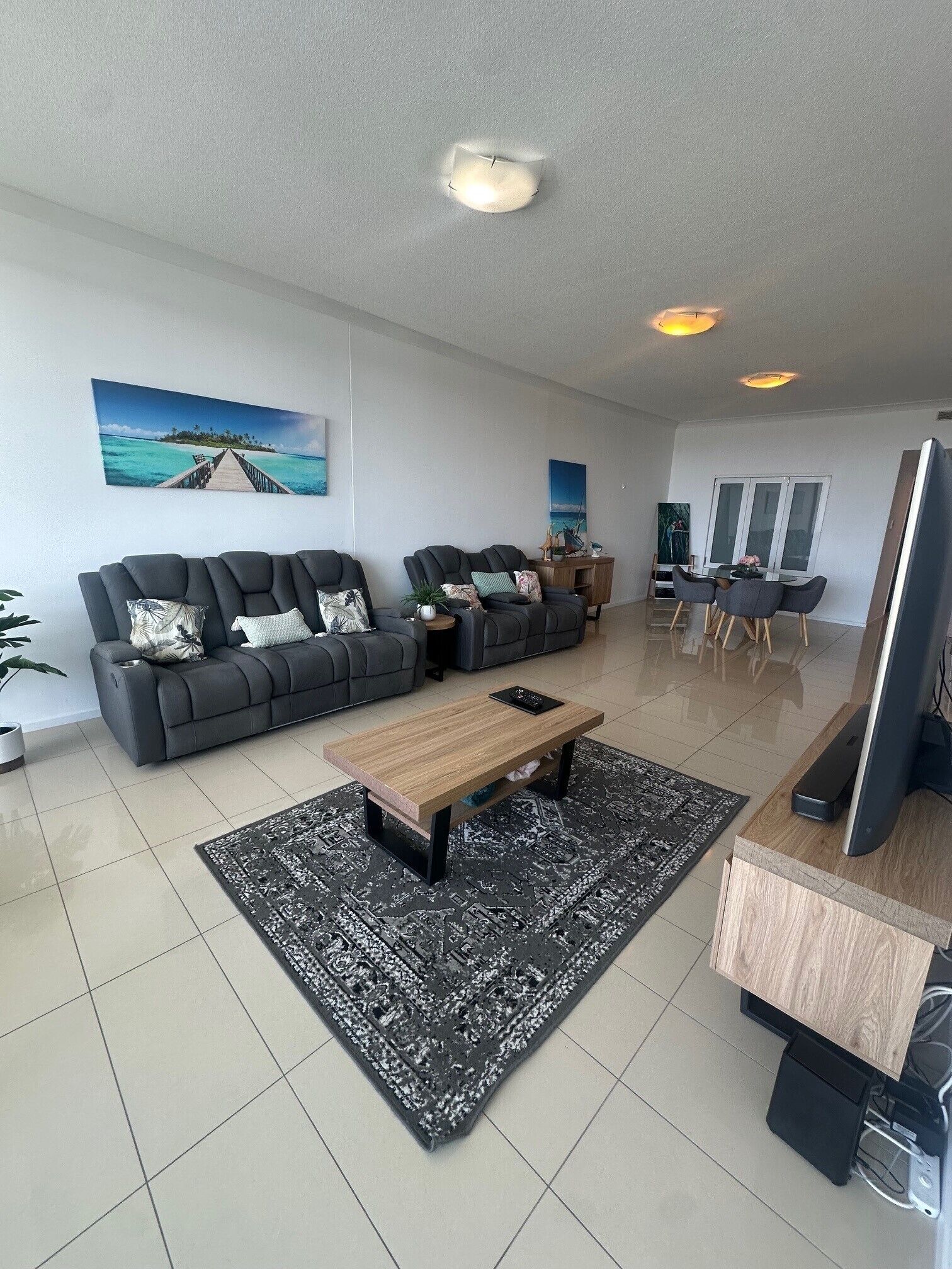 Uma sala de estar moderna com um conjunto de sofá, uma mesa de centro e um espaço de jantar com cadeiras.