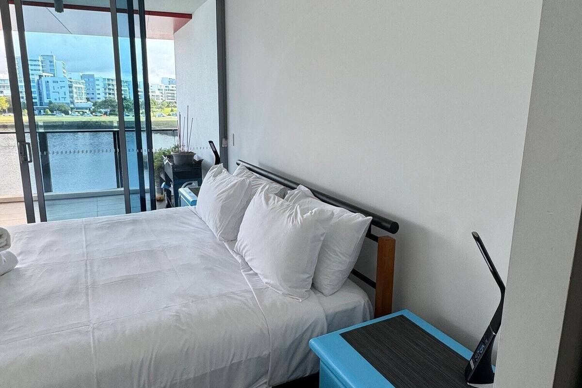 Ein Hotelzimmer mit Bett, Schreibtisch und Blick auf ein Gewässer sowie Gebäude.