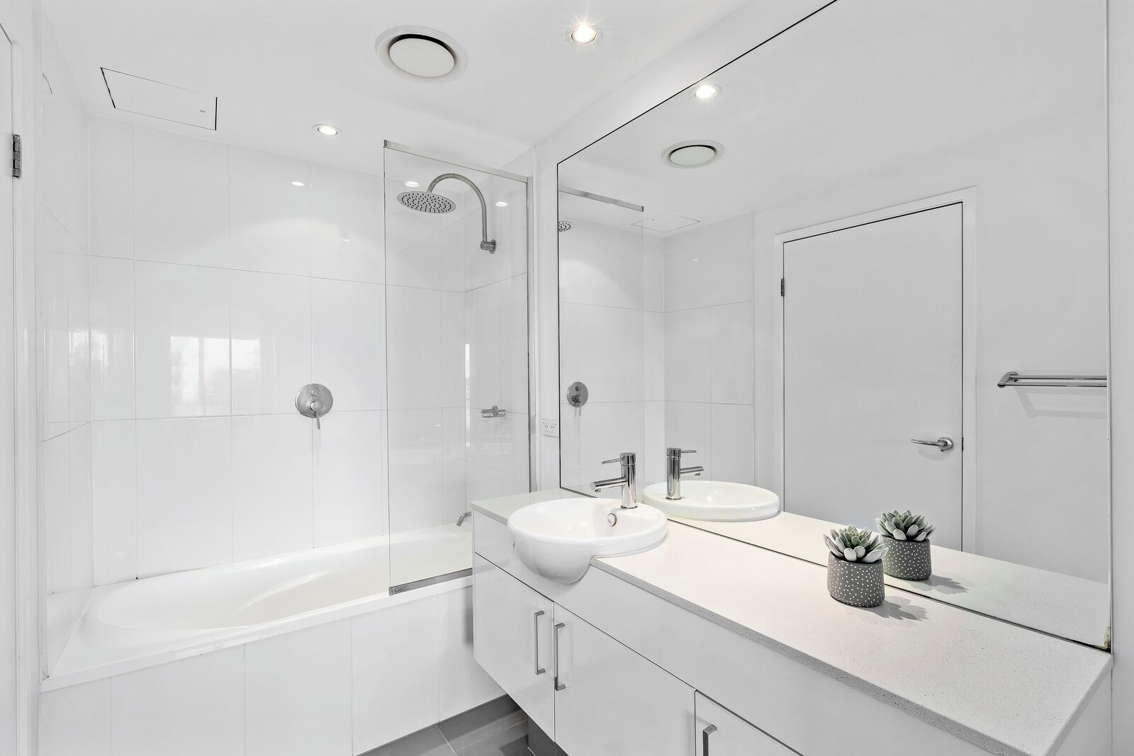 Een moderne badkamer met een badkuip, twee wasbakken, een douche en een grote spiegel.