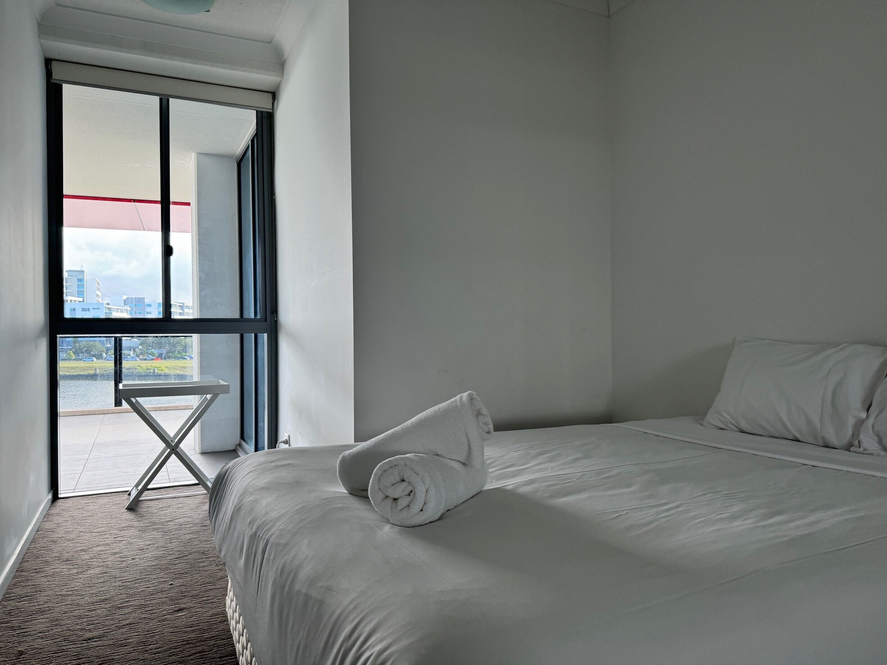 Une chambre d’hôtel avec un grand lit, une petite table et une vue sur les immeubles par la fenêtre.