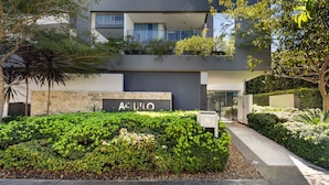 A modern building with a sign reading "AQUILO". - Harbour Quays Apartments (Biggera Waters)