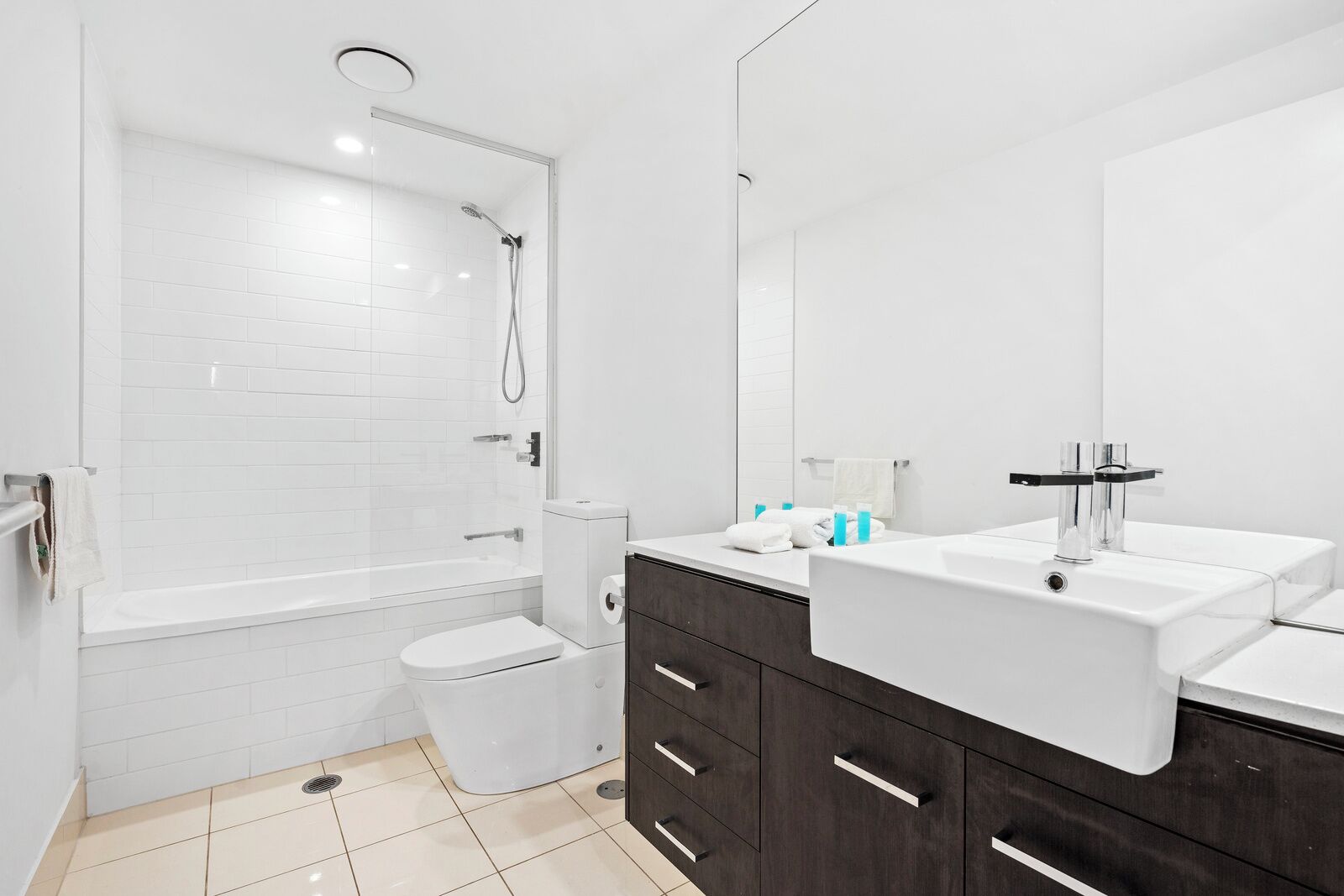 A modern bathroom with a shower, toilet, vanity, and a large mirror.