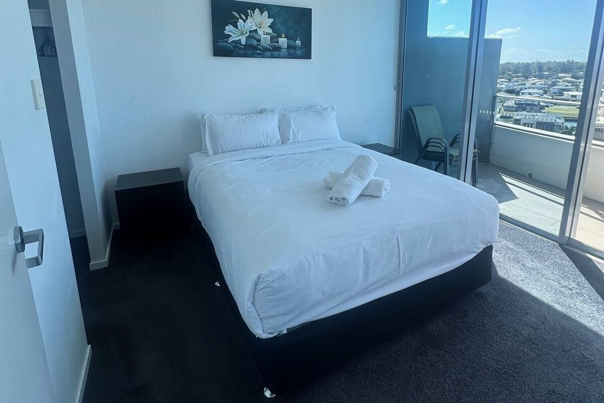 Ein modernes Hotelzimmer mit einem großen Bett, einem Gemälde und einem Balkon mit Blick auf die Stadt.