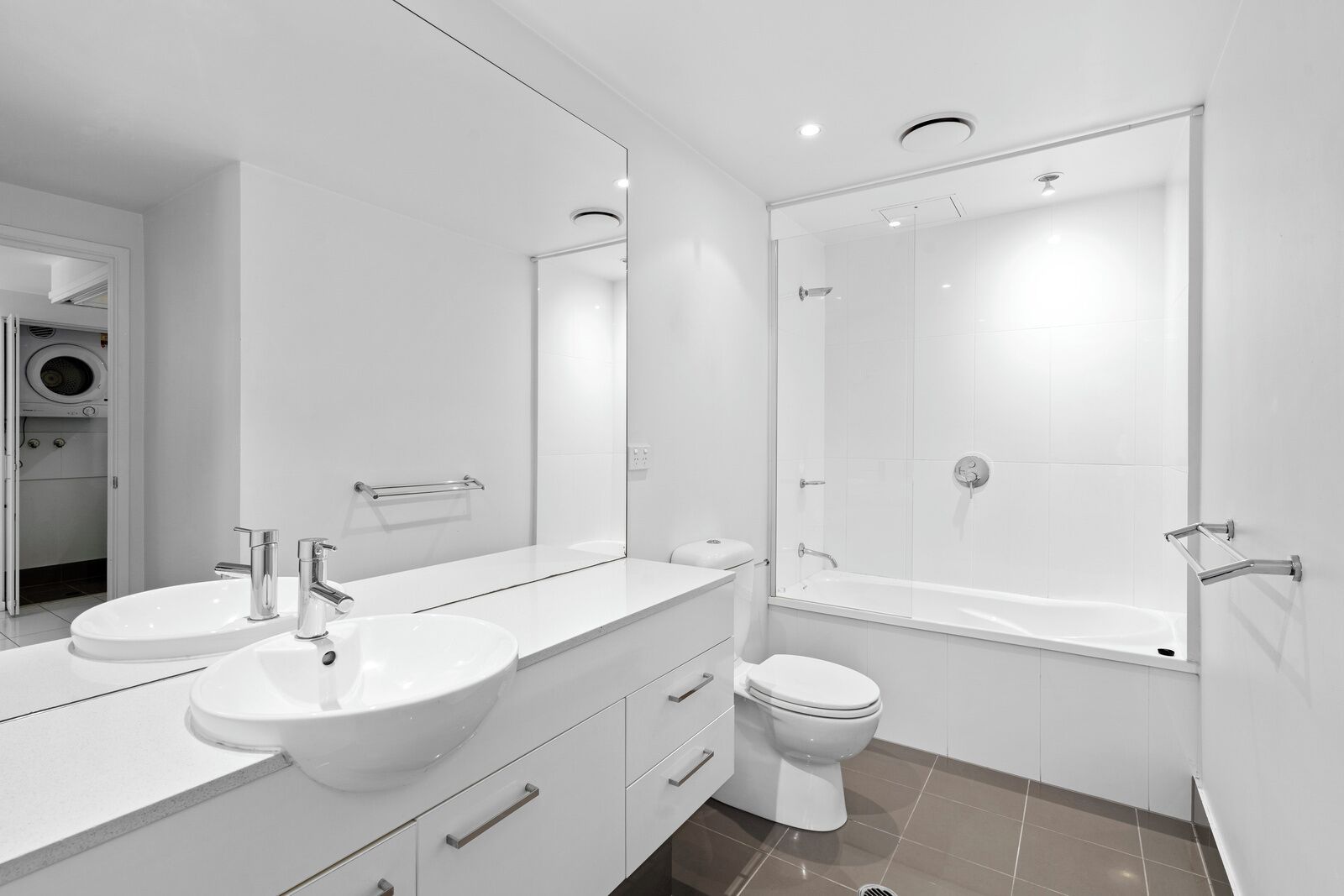 A modern bathroom with two sinks, a toilet, and a bathtub.
