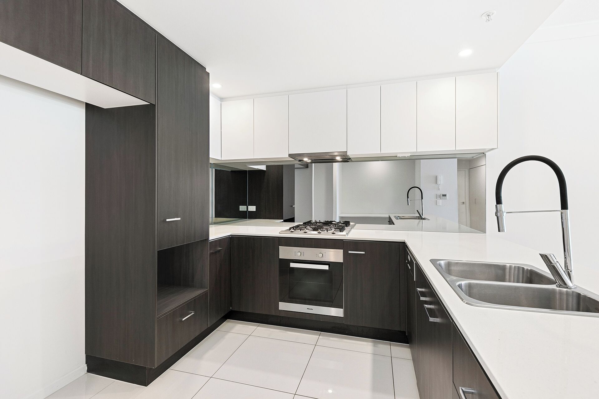A modern kitchen with dark cabinetry, a stainless steel sink, and a built-in oven.