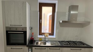A compact kitchen with a built-in oven, a gas stove, and a window with a view of the street. - A1 SOLE - APARTMENT WITH 6 BEDS (Balestrate)